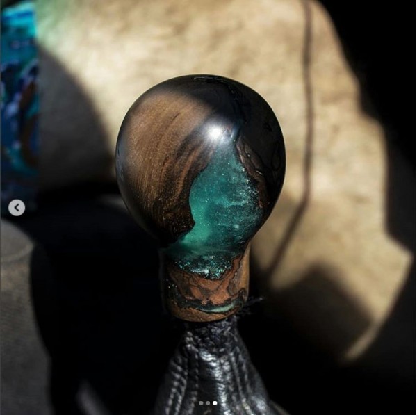Le pommeau du levier de vitesse est une pièce de noyer avec un noeud qui a fait éclater le bois et a créé une crevasse dans laquelle on a coulé une résine qu'on a teintée en bleu turquoise pailleté. On a ensuite sculpté le pommeau au tour à bois